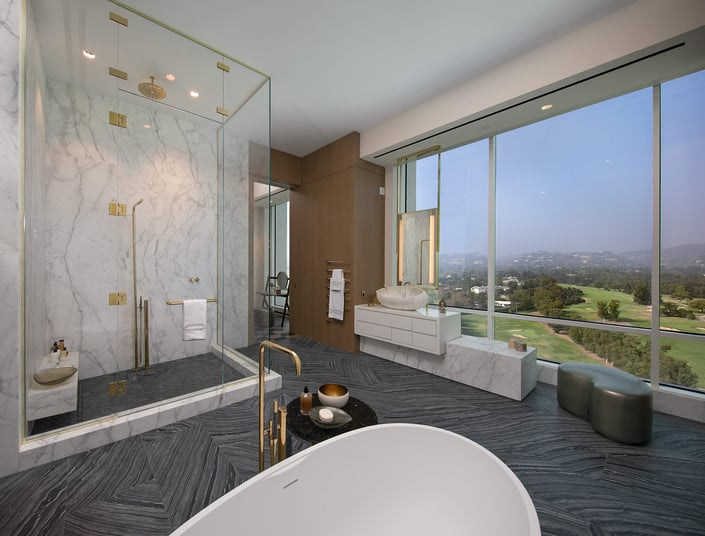 A marble and tile bathroom with a large window and view of the city