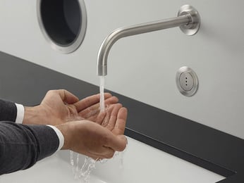 Person washing hands under VOLA faucet